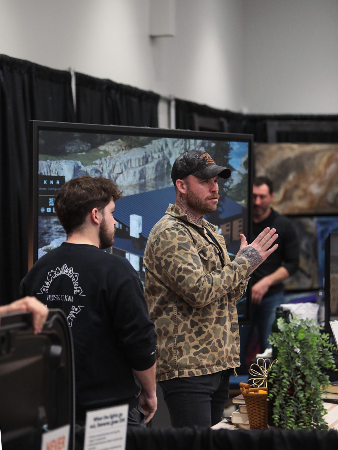 An exhibitor explaining his work to a visitor at a booth